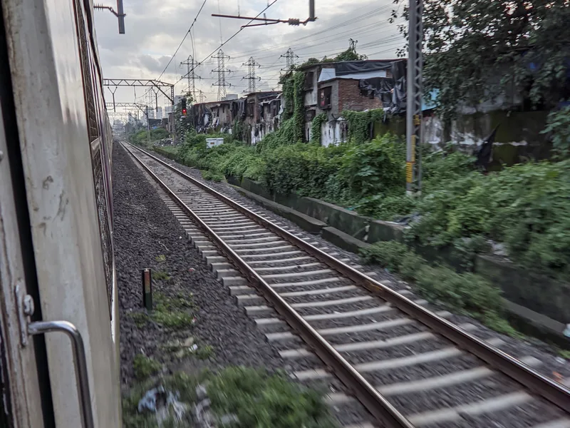 Kurla red light area, Mumbai — worn trackside buildings seen from a passing local train near Kurla